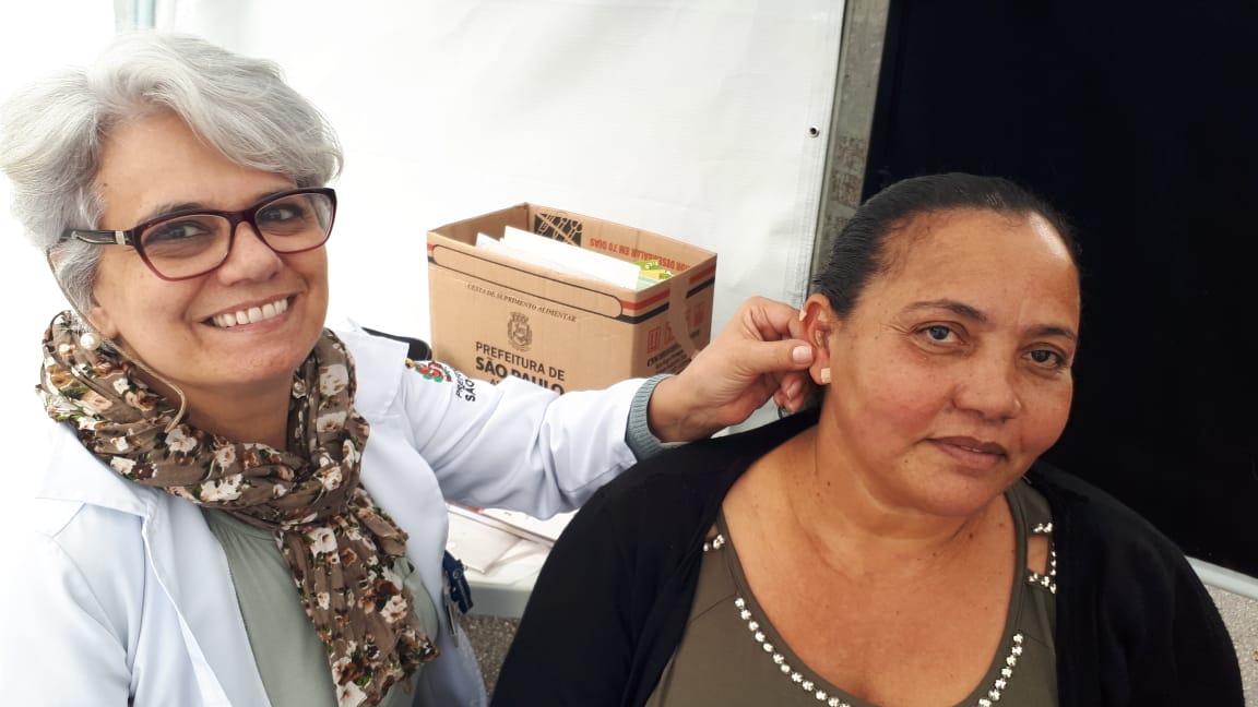 Juliana Antunes fazendo atendimento de acupuntura auricular.